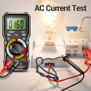 ANENG Digital multimeter measuring AC current with a light bulb and electrical components in the background.