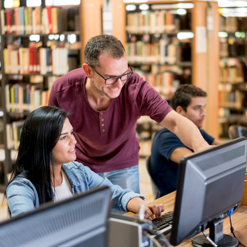 A librarian showing something on the computer to a visitor